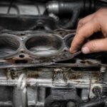 Dłoń mechanika sprawdza zużytą uszczelkę na bloku silnika samochodowego
