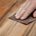 Dłoń szlifująca drewnianą deskę papierem ściernym